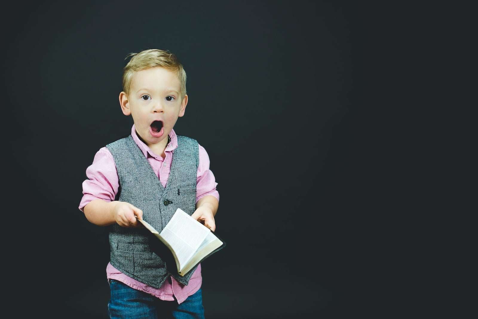 boy wearing gray vest and pink dress shirt holding book - how to share your faith with confidence and grace